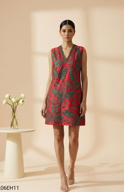 Woman wearing a red dress with green leaf patterns on a beige background